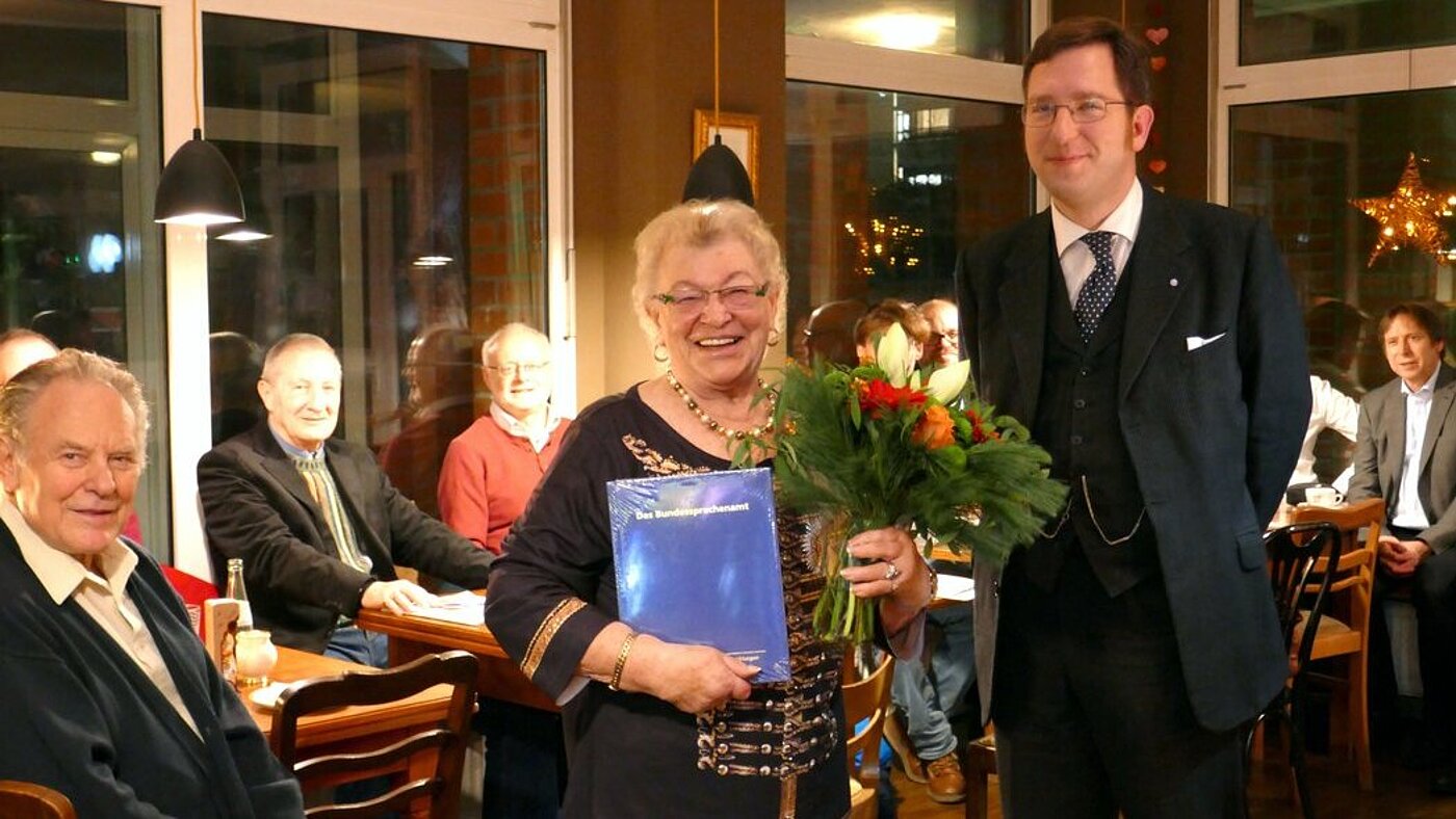 Mitgliederversammlung der StOGr. Hürth im weihnachtlichen Ambiente Für Frau Dächer gab es viel Beifall, einen Jubiläumsband über das Bundessprachenamt und einen Blumenstrauß (links im Bild: Eveline Dächer, rechts im Bild: RAmtm Matthias Sommer). Mitgliederversammlung der StOGr. Hürth im weihnachtlichen Ambiente